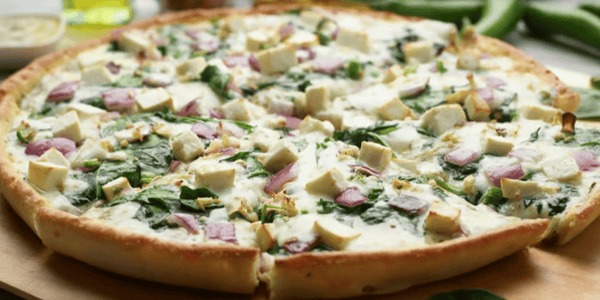 Achari Pesto Paneer Pizza with spinach and red onion on a light and airy crust.