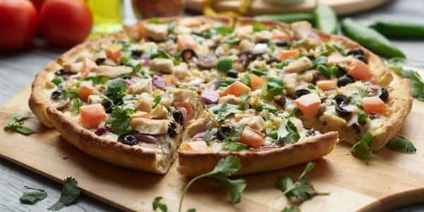 Indian Chicken Pizza with colorful toppings on a wooden board, ready to eat.