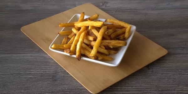 Seasoned fries in a white dish, presented on a wooden cutting board.