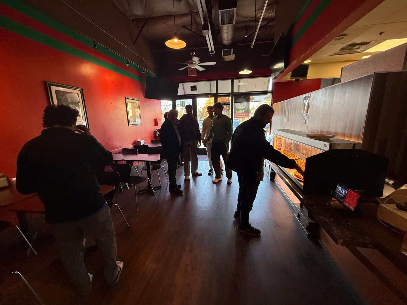 People at an unlimited pizza buffet choosing slices from a display case for just $10.