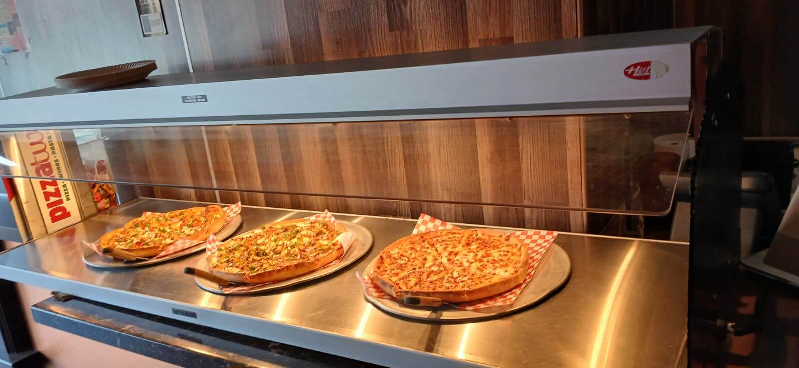 Pizza Hut buffet with three pizzas on display. Pizza, Wings, Pasta.